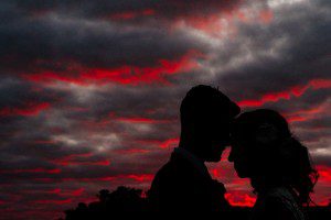 sunset photograph with bride and groom silhouetted against a beautiful big pink sky