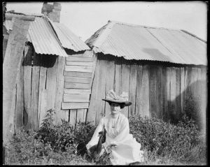 old photo of a woman with a goose near a timber building at Kimo Estate