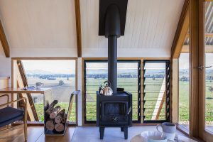 internal image of jar's ecohut, wood fire and wood to burn in architectural feature. expansive views of the river flats in the background