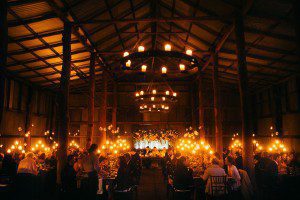 Large rustic wedding shed filled with guests from Sydney with long tables at a large wedding, candles everywhere