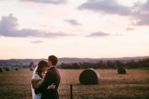 Sydney bride and groom in paddock with hay bales after their wedding ceremony.