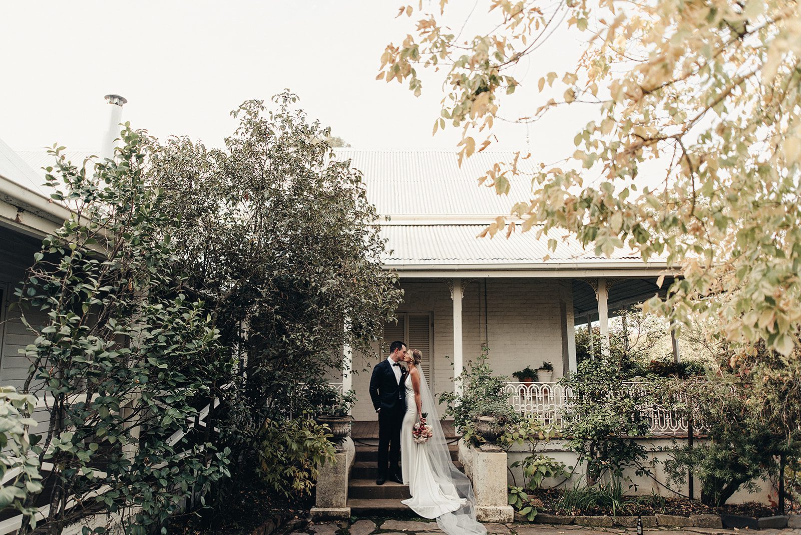 Bride and groom after the wedding ceremony, standing on the steps of a historic country home after the wedding ceremony.