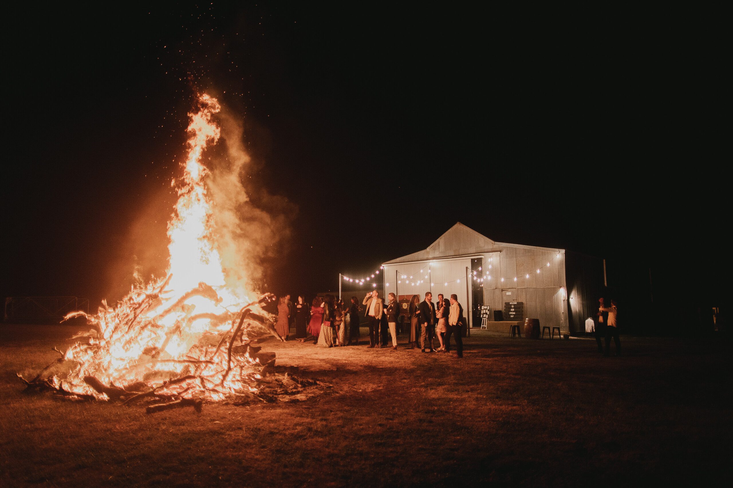 A raging bonfire at the Grain Shed at Kimo Estate with the reception venue in the background