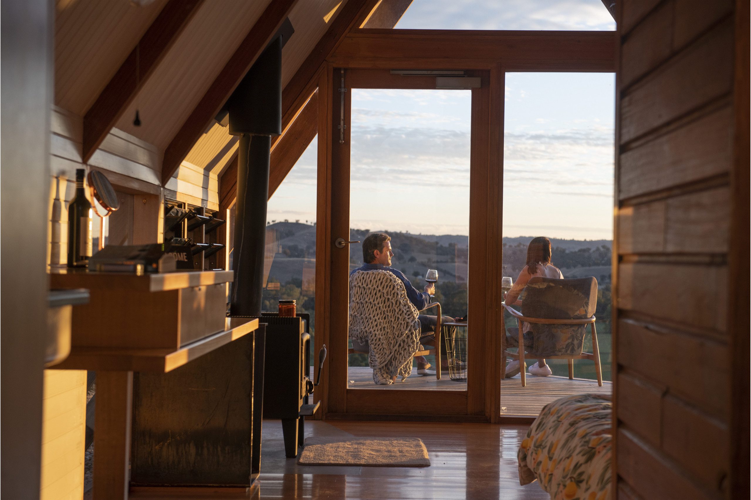 A couple in the accommodation enjoying a wine and the beautiful view in the evening light, nearly sunset