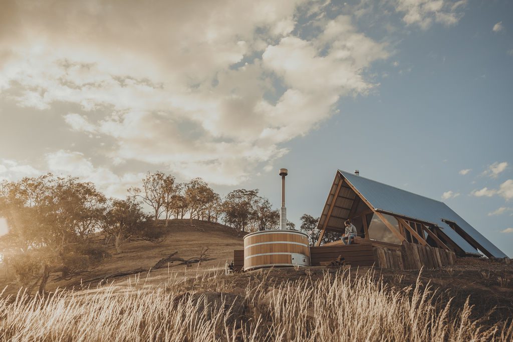 KimoEstate_SweenysHut_DeclanBlackallPhotography_031219_0009 → Kimo Estate Gundagai The Kimo Estate Eco hut Aframe accommodation in the afternoon light with a guest enjoying the expansive views