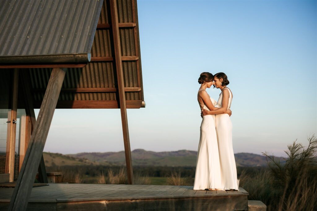 Brides on the deck at JR's Ecohut embracing with a big view behind them