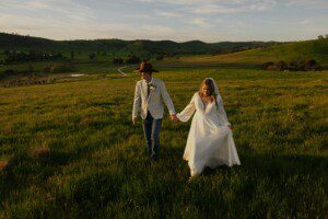 couple walking up a hill on their wedding day. A beautiful country scene in the background