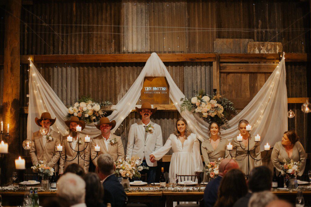 New husband and wife standing at the head bridal table at their wedding reception