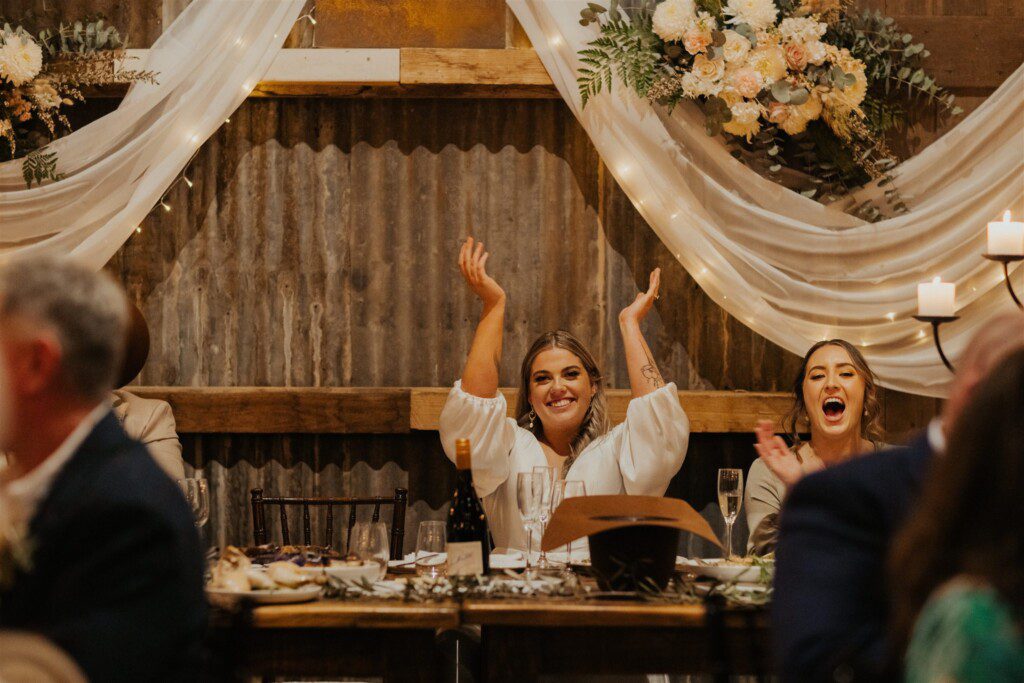 the bride applauding a speech by her bridesmaid