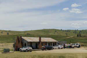 A country scene with a set of shearers quarters. There are multiple cars parked and people busying themselves