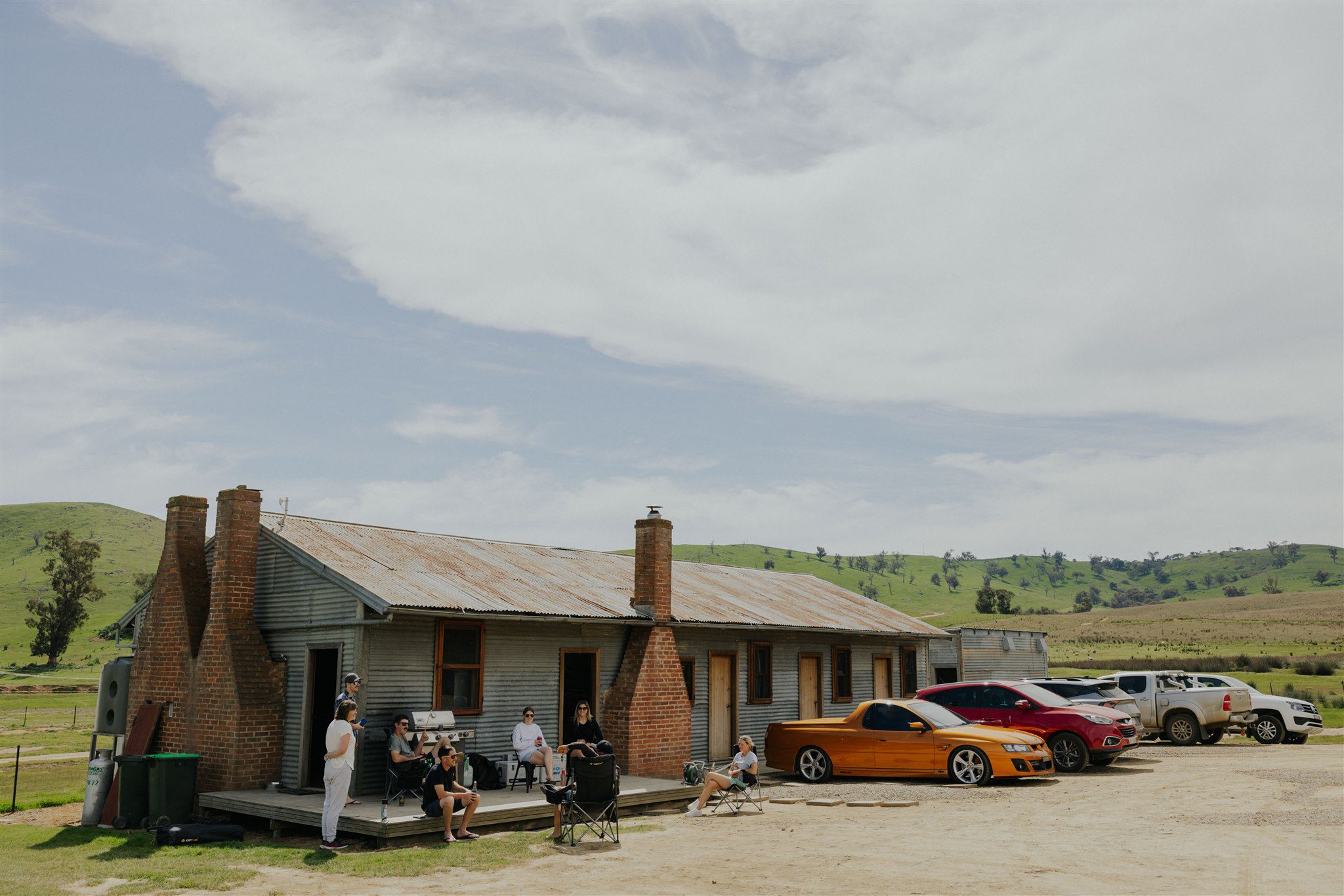 a country scene win hills in the background and a building with guests in the foreground